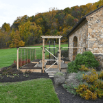 Raised bed garden with curved perennial beds, a berry trellis, and integrated fencing