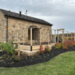 Raised bed garden with curved perennial beds, a berry trellis, and integrated fencing