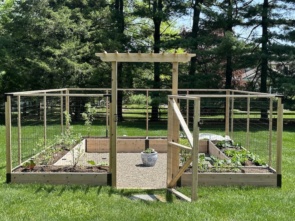 An enclosed raised bed garden with a central gravel pathway