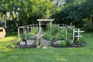 Front view of raised bed garden with open gate and greenery